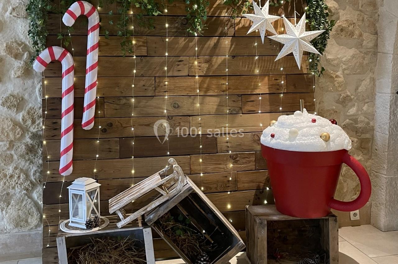 Décoration festive avec cannes en sucre, étoiles lumineuses, tasse géante et caisses en bois sur fond de guirlandes.