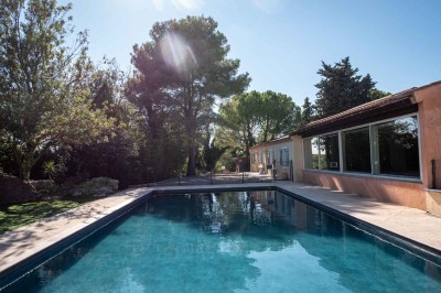 Vue aérienne d'une maison avec toit en tuiles, piscine rectangulaire et jardin arboré dans un cadre rural.
