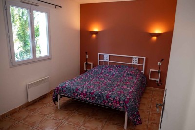 Vue aérienne d'une maison avec toit en tuiles, piscine rectangulaire et jardin arboré dans un cadre rural.