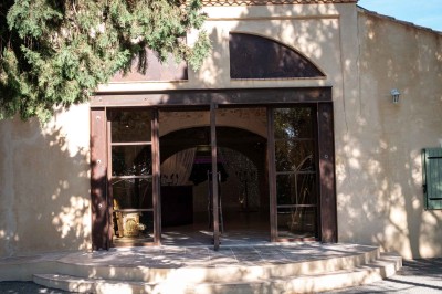 Vue aérienne d'une maison avec toit en tuiles, piscine rectangulaire et jardin arboré dans un cadre rural.