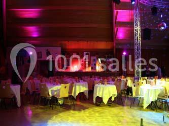 Salle de réception décorée avec des tables dressées et éclairage d'ambiance violet.
