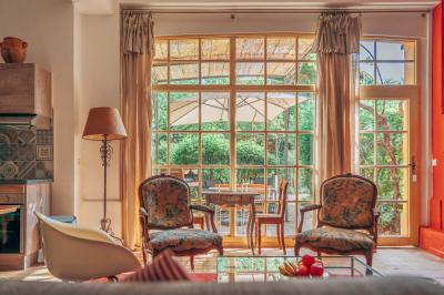 Miniature Location salle Servian (Hérault) - Château Hermitage de Combas #31 Chambre lumineuse avec lit double, tête de lit rouge, murs en pierre, grandes fenêtres et mobilier classique.