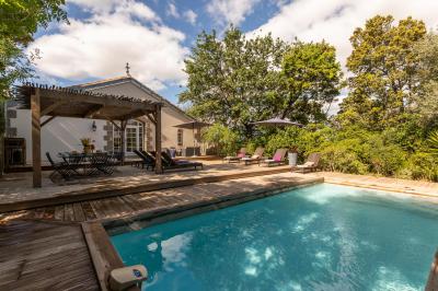 Miniature Location salle Servian (Hérault) - Château Hermitage de Combas #24 Chambre lumineuse avec lit double, tête de lit rouge, murs en pierre, grandes fenêtres et mobilier classique.