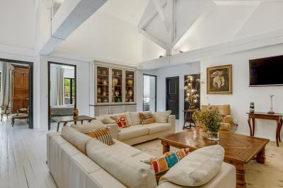 Miniature Location salle Servian (Hérault) - Château Hermitage de Combas #26 Chambre lumineuse avec lit double, tête de lit rouge, murs en pierre, grandes fenêtres et mobilier classique.