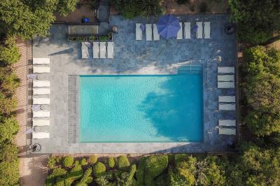 Miniature Location salle Servian (Hérault) - Château Hermitage de Combas #16 Chambre lumineuse avec lit double, tête de lit rouge, murs en pierre, grandes fenêtres et mobilier classique.