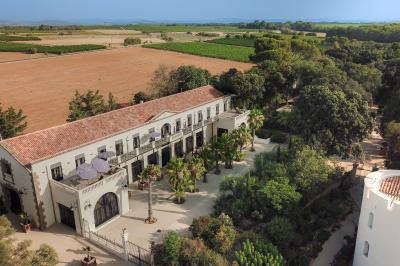 Miniature Location salle Servian (Hérault) - Château Hermitage de Combas #5 Chambre lumineuse avec lit double, tête de lit rouge, murs en pierre, grandes fenêtres et mobilier classique.