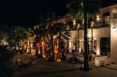 Miniature Location salle Servian (Hérault) - Château Hermitage de Combas #14 Chambre lumineuse avec lit double, tête de lit rouge, murs en pierre, grandes fenêtres et mobilier classique.
