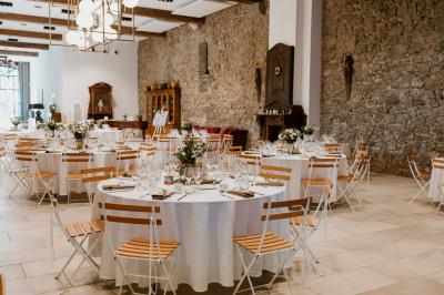 Miniature Location salle Servian (Hérault) - Château Hermitage de Combas #11 Chambre lumineuse avec lit double, tête de lit rouge, murs en pierre, grandes fenêtres et mobilier classique.