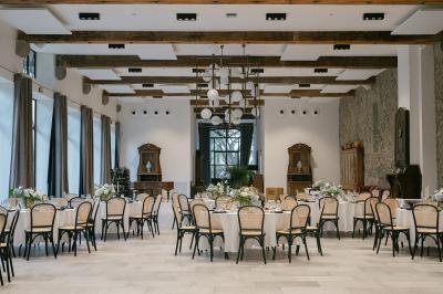 Miniature Location salle Servian (Hérault) - Château Hermitage de Combas #12 Chambre lumineuse avec lit double, tête de lit rouge, murs en pierre, grandes fenêtres et mobilier classique.