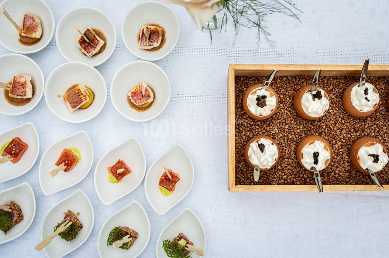 Assortiment de bouchées gastronomiques présentées dans des assiettes individuelles sur une table blanche.