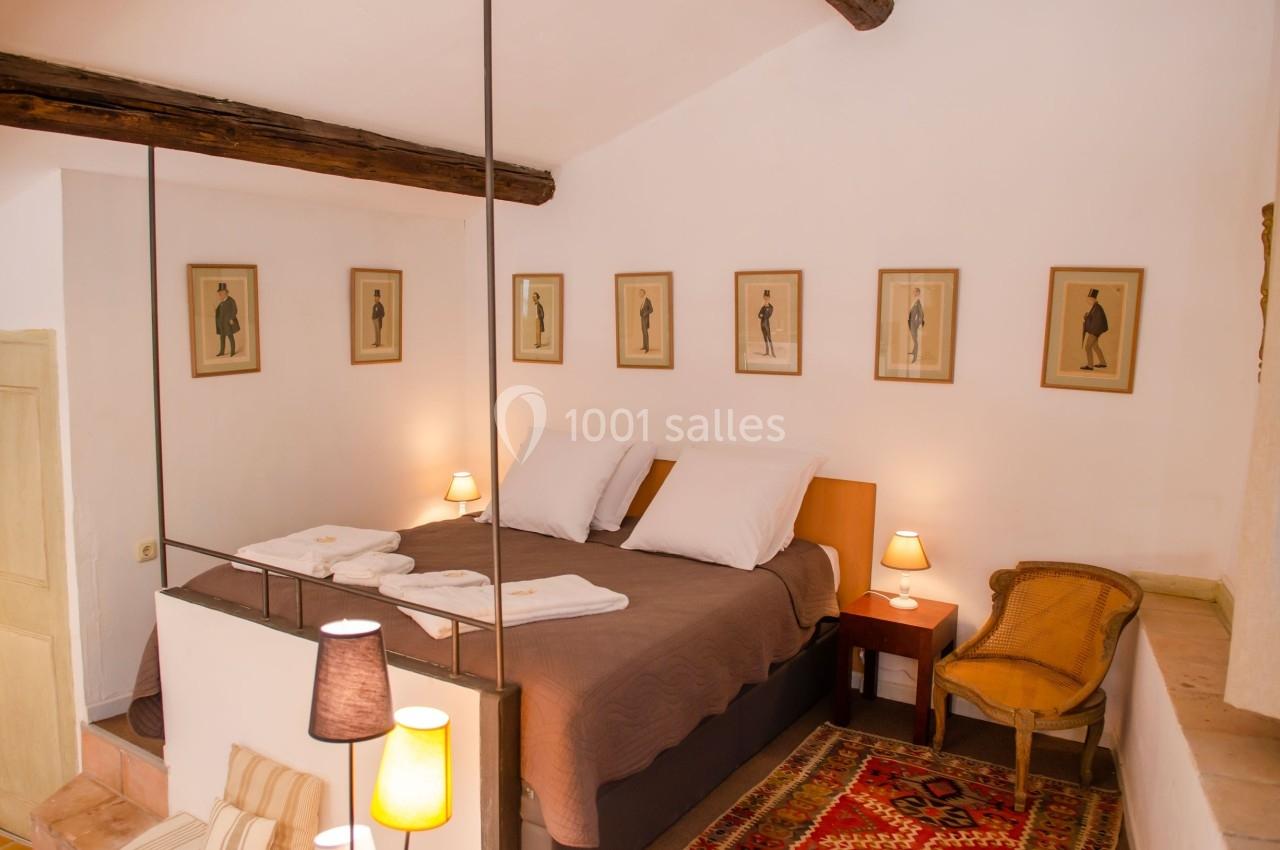 Chambre lumineuse avec un lit double, des lampes de chevet, des cadres au mur et un tapis coloré au sol.