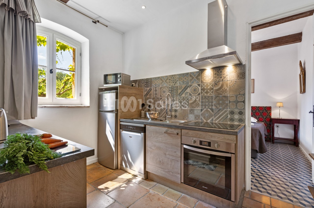 Cuisine lumineuse avec plan de travail en bois, carrelage décoratif, électroménagers modernes et vue sur un jardin.