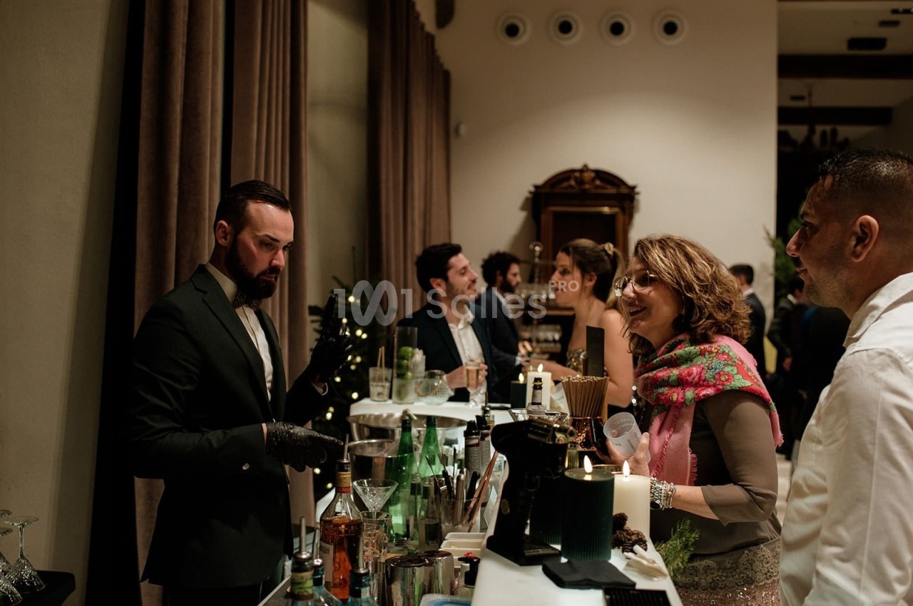 Un barman sert des boissons à des invités lors d'un événement dans un cadre élégant et chaleureux.