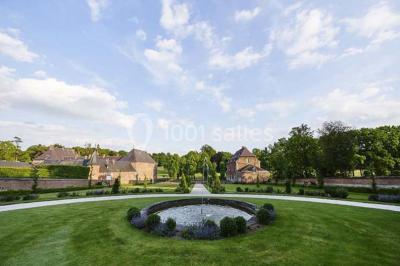 Cour pavée éclairée par des bougies et lumières chaudes, avec un bâtiment historique en arrière-plan, de nuit.