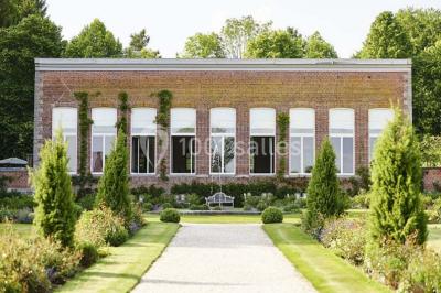 Cour pavée éclairée par des bougies et lumières chaudes, avec un bâtiment historique en arrière-plan, de nuit.