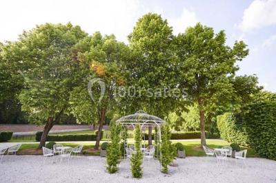 Cour pavée éclairée par des bougies et lumières chaudes, avec un bâtiment historique en arrière-plan, de nuit.