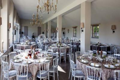Cour pavée éclairée par des bougies et lumières chaudes, avec un bâtiment historique en arrière-plan, de nuit.