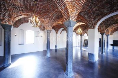 Cour pavée éclairée par des bougies et lumières chaudes, avec un bâtiment historique en arrière-plan, de nuit.