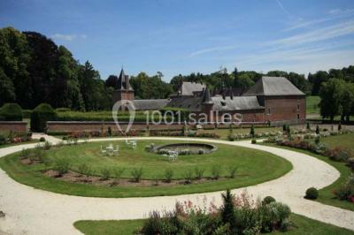 Cour pavée éclairée par des bougies et lumières chaudes, avec un bâtiment historique en arrière-plan, de nuit.
