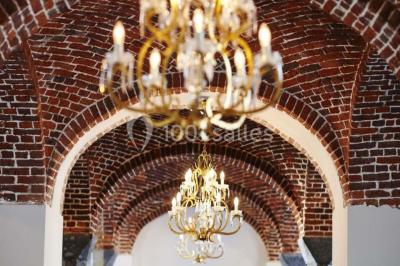 Cour pavée éclairée par des bougies et lumières chaudes, avec un bâtiment historique en arrière-plan, de nuit.