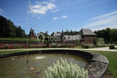 Cour pavée éclairée par des bougies et lumières chaudes, avec un bâtiment historique en arrière-plan, de nuit.