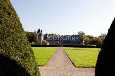 Cour pavée éclairée par des bougies et lumières chaudes, avec un bâtiment historique en arrière-plan, de nuit.