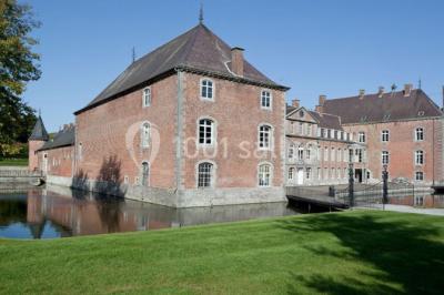 Cour pavée éclairée par des bougies et lumières chaudes, avec un bâtiment historique en arrière-plan, de nuit.