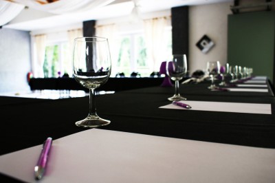 Miniature Location salle Flémalle (Liège) - Salons Ypsilon #26 Salle de conférence lumineuse avec des rangées de chaises noires, un écran de projection et un tableau blanc.