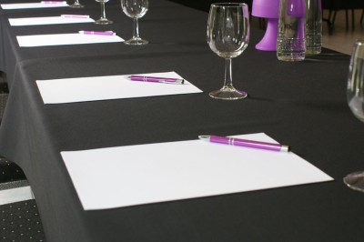 Miniature Location salle Flémalle (Liège) - Salons Ypsilon #27 Salle de conférence lumineuse avec des rangées de chaises noires, un écran de projection et un tableau blanc.