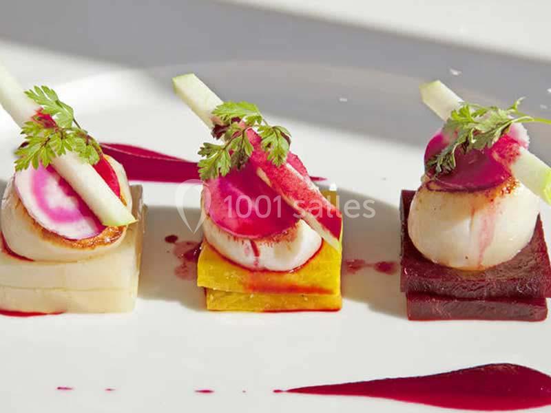 Trio de noix de Saint-Jacques sur des cubes de légumes colorés, décorées de fines tranches et herbes fraîches.