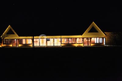 Miniature Location salle Cliponville (Seine-Maritime) - Le Clos Masure Simon #24 Bâtiment illuminé de nuit avec des façades vitrées et un toit en pente, entouré d'obscurité.