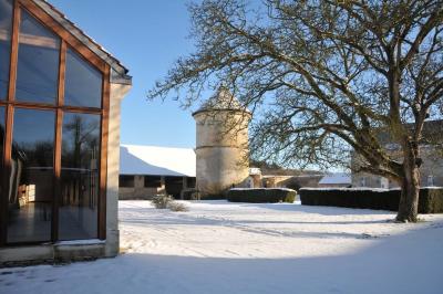 Miniature Location salle Saint-Vaast-lès-Mello (Oise) - Le Clos Barisseuse #53 Cour enneigée avec bâtiments en pierre, un pigeonnier cylindrique et des arbres nus sous un ciel dégagé.