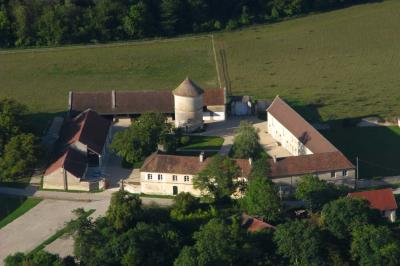 Miniature Location salle Saint-Vaast-lès-Mello (Oise) - Le Clos Barisseuse #13 Cour enneigée avec bâtiments en pierre, un pigeonnier cylindrique et des arbres nus sous un ciel dégagé.
