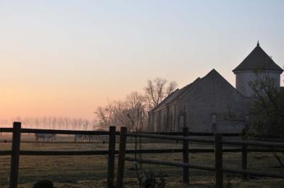 Miniature Location salle Saint-Vaast-lès-Mello (Oise) - Le Clos Barisseuse #32 Cour enneigée avec bâtiments en pierre, un pigeonnier cylindrique et des arbres nus sous un ciel dégagé.