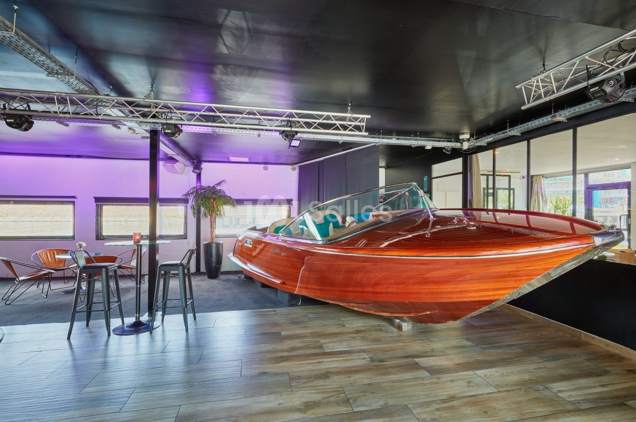 Bateau en bois verni aménagé en mobilier dans un espace intérieur moderne avec éclairage violet.