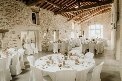 Miniature Location salle Rions (Gironde) - Domaine Pascaud #4 Salle de réception lumineuse avec tables rondes dressées, nappes blanches, chaises en bois et décorations florales.