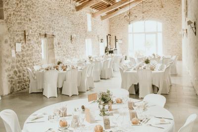 Miniature Location salle Rions (Gironde) - Domaine Pascaud #2 Salle de réception lumineuse avec tables rondes dressées, nappes blanches, chaises en bois et décorations florales.