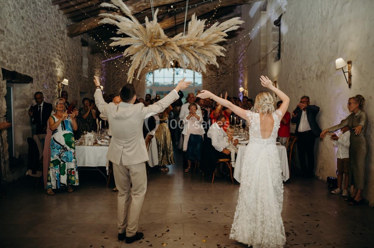 Un couple danse sous un décor suspendu dans une salle en pierre, entouré d'invités applaudissant.
