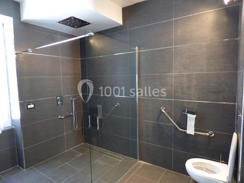 Salle de bain moderne avec douche à l'italienne, barres d'appui murales et toilettes accessibles.