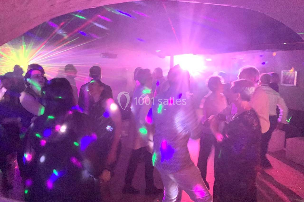 Personnes dansant dans une salle sombre éclairée par des lumières colorées et des effets laser.