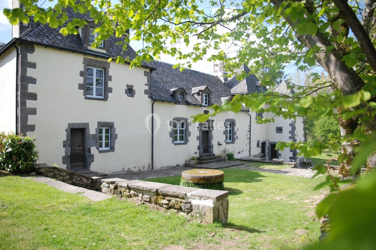 Location salle Charbonnières-les-Varennes (Puy-de-Dôme) - Manoir de Veygoux #4 Façade d'une maison en pierre de style traditionnel, entourée de verdure et éclairée par la lumière du jour.