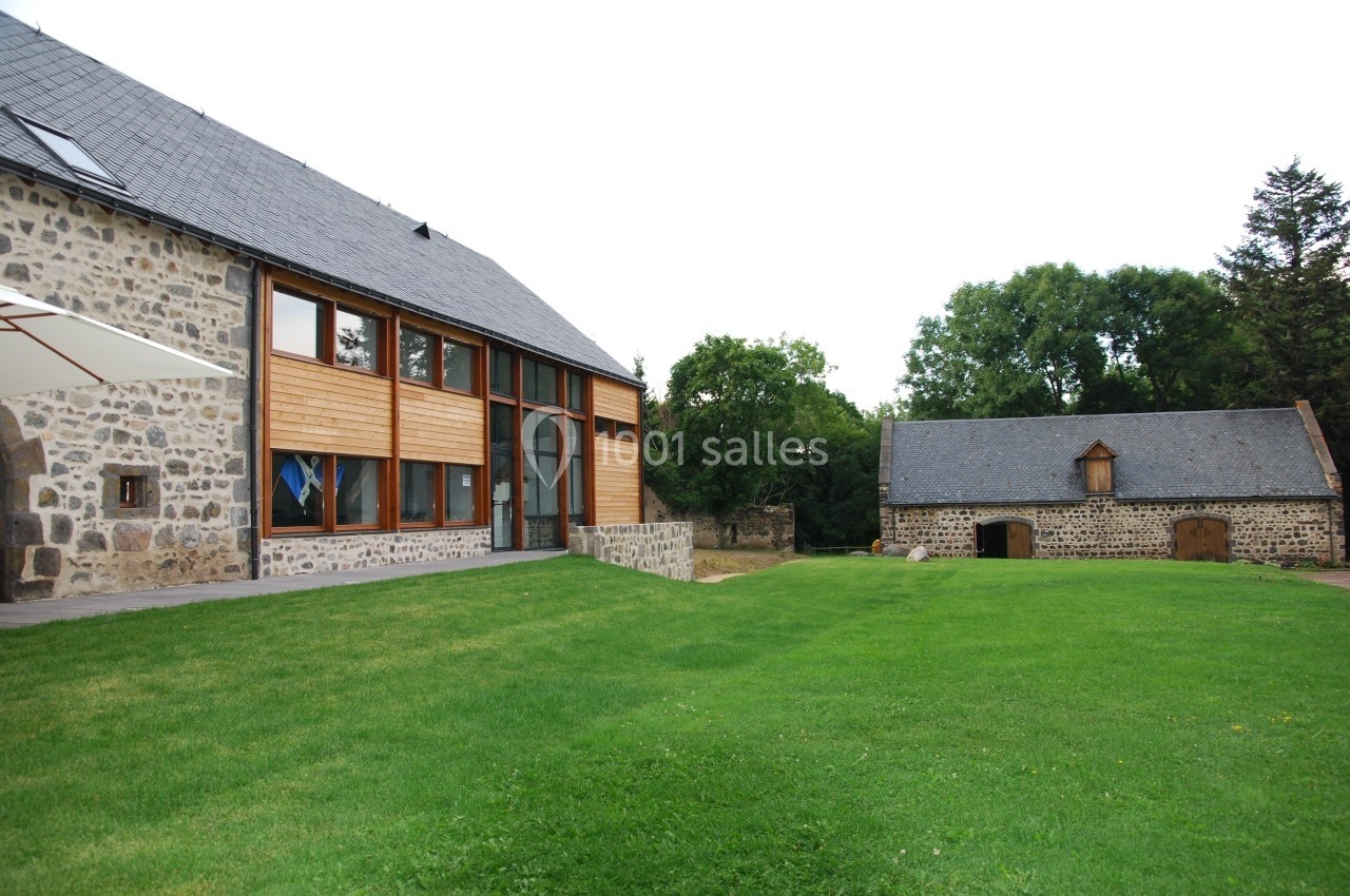 Location salle Charbonnières-les-Varennes (Puy-de-Dôme) - Manoir de Veygoux #6 Bâtiments en pierre rénovés avec une façade en bois, entourés d'une pelouse et d'arbres.