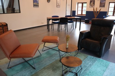 Salle de réunion équipée de chaises rouges et noires, d'un vidéoprojecteur et d'un écran blanc.