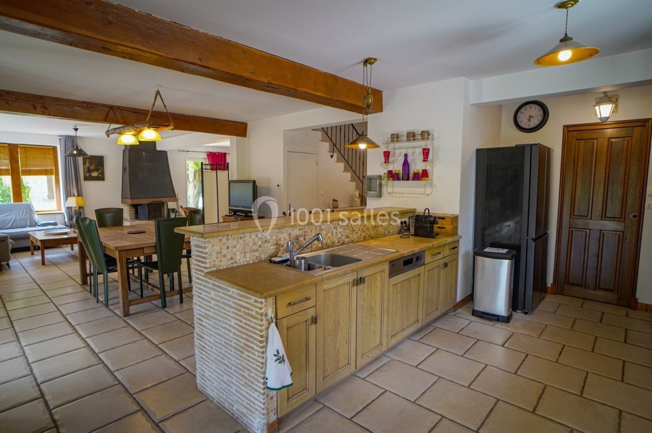 Cuisine ouverte avec un plan de travail en bois, vue sur une salle à manger et un salon dans un intérieur lumineux.