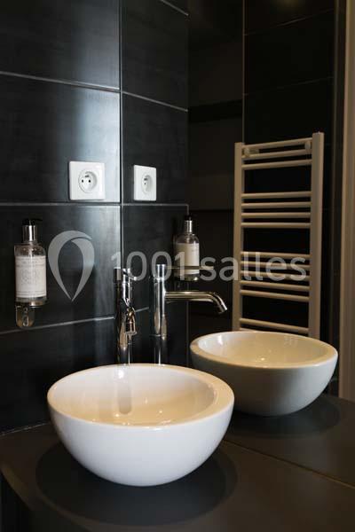 Location salle Pomérols (Hérault) - Domaine Fon de Rey #19 Deux lavabos blancs ronds sur un plan noir, avec un robinet chromé, un miroir et un sèche-serviettes mural.