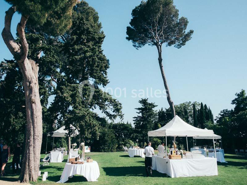 Location salle Pomérols (Hérault) - Domaine Fon de Rey #7 Des tables sous des tentes blanches sont installées dans un jardin verdoyant par une journée ensoleillée.