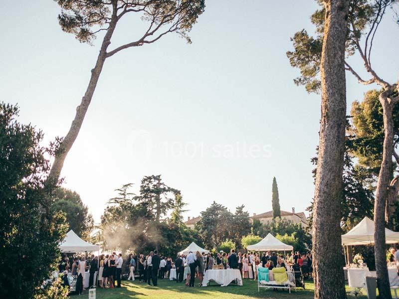 Location salle Pomérols (Hérault) - Domaine Fon de Rey #9 Groupe de personnes rassemblées dans un jardin sous des tentes blanches, entouré d'arbres et de végétation.