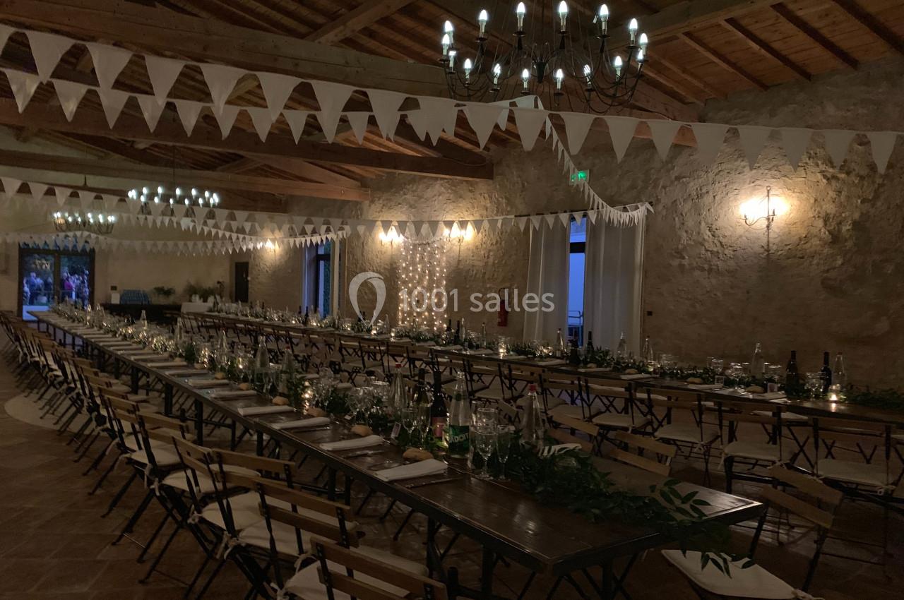 Location salle Pomérols (Hérault) - Domaine Fon de Rey #23 Grande salle décorée pour un événement, avec longues tables en bois, guirlandes lumineuses et fanions suspendus.