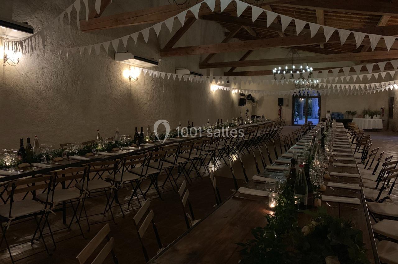 Location salle Pomérols (Hérault) - Domaine Fon de Rey #24 Grande salle décorée pour un événement, avec longues tables dressées, guirlandes de fanions et éclairage tamisé.