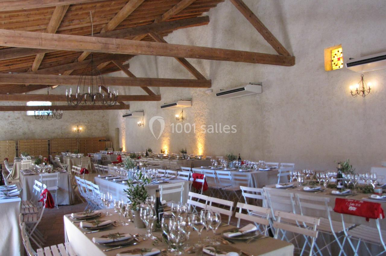 Location salle Pomérols (Hérault) - Domaine Fon de Rey #27 Salle de réception avec tables dressées, chaises blanches, poutres apparentes et éclairage chaleureux.